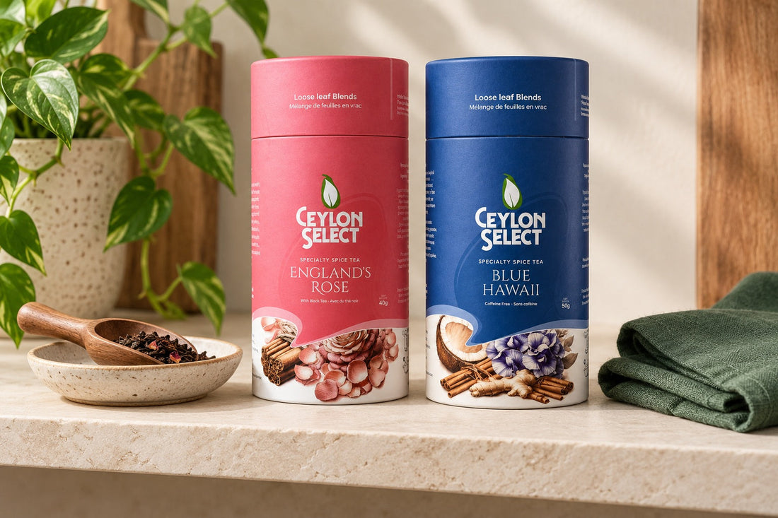 Pink England’s Rose and navy Blue Hawaii Ceylon Select canisters on a shaded shelf with a dry tea scoop and green linen.